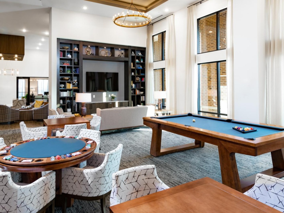 a room with a pool table and chairs